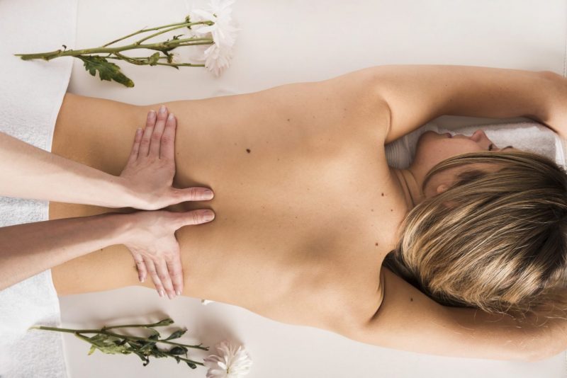 Vue grand angle femme qui recoit massage du dos therapeute